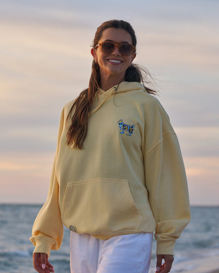 Woman in yellow hoodie with the ocean in the background