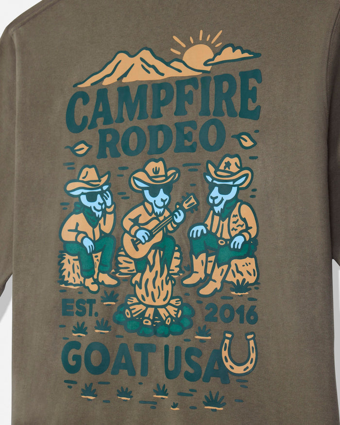 Close-up of a brown long-sleeve t-shirt featuring a colorful graphic print with the text 'CAMPFIRE RODEO', 'EST. 2016', and 'GOAT USA' with cartoon goats in cowboy attire around a campfire.