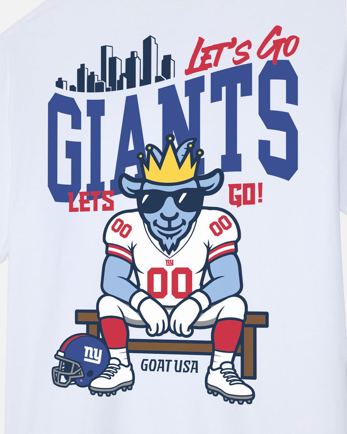 White t-shirt featuring a cartoon goat mascot wearing a gold crown and black sunglasses, sitting on a bench with a New York Giants helmet and 'GOAT USA' text. The graphic includes the words 'LET'S GO GIANTS' in red and blue.