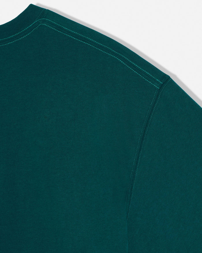 Close-up of a dark teal green crewneck sweatshirt showing the shoulder seam and contrast stitching against a white background.