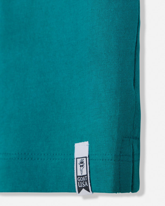 Close-up of a teal garment with a brand label on a white background