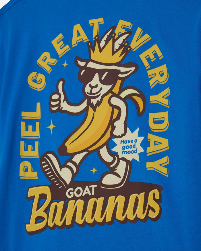 A close-up of a blue graphic t-shirt featuring a cartoon goat character wearing a banana suit, sunglasses, and a crown, with the text 'PEEL GREAT EVERYDAY GOAT Bananas' and a starburst that says 'Have a good mood'.