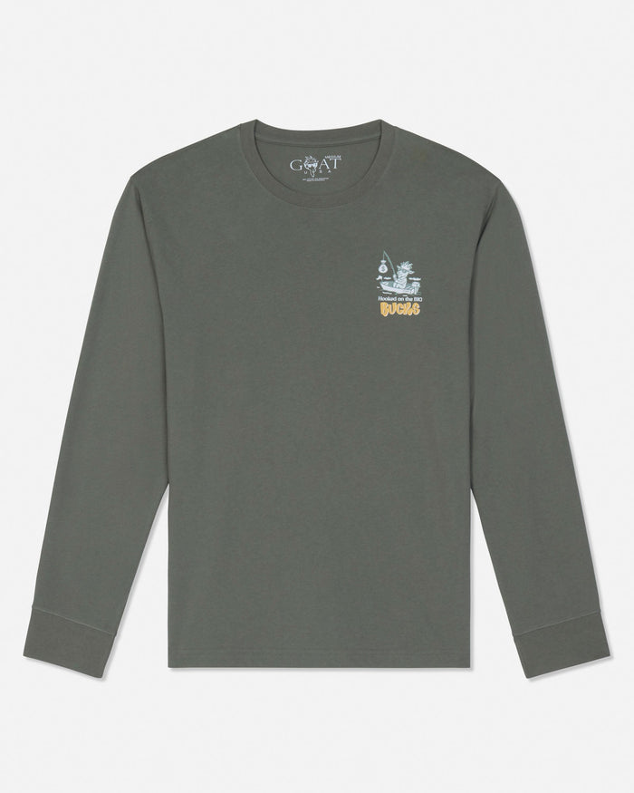 A dark olive green long-sleeve t-shirt by GOAT USA, featuring a small graphic on the left chest with a white ship and the word 'BUCKS' in yellow, displayed on a clean white background.