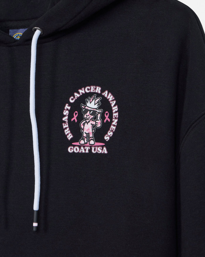 Close-up of a black hoodie featuring a circular pink and white embroidered graphic on the chest with the text 'BREAST CANCER AWARENESS' and 'GOAT USA' around a cartoon goat character.