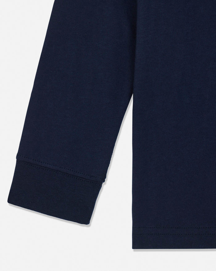 Close-up of a navy blue long-sleeve garment, showing the cuff of one sleeve and the hem of the other, on a light gray background.