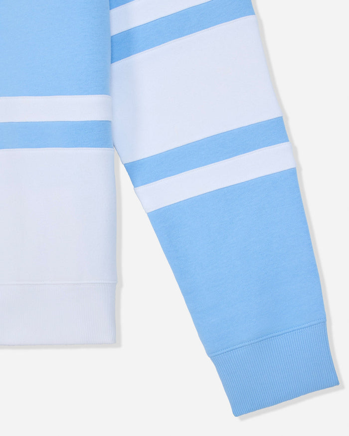 Close-up of a light blue and white striped long-sleeve garment, showing part of the sleeve with horizontal stripes and ribbed cuffs on a light gray background.