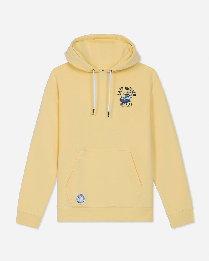 A pale yellow pullover hoodie with white drawstrings, a kangaroo pocket, and a blue and black graphic on the left chest reading 'LAZY CHILLIN NAP CLUB' alongside a small circular patch near the lower left hem, shown on a light gray background.