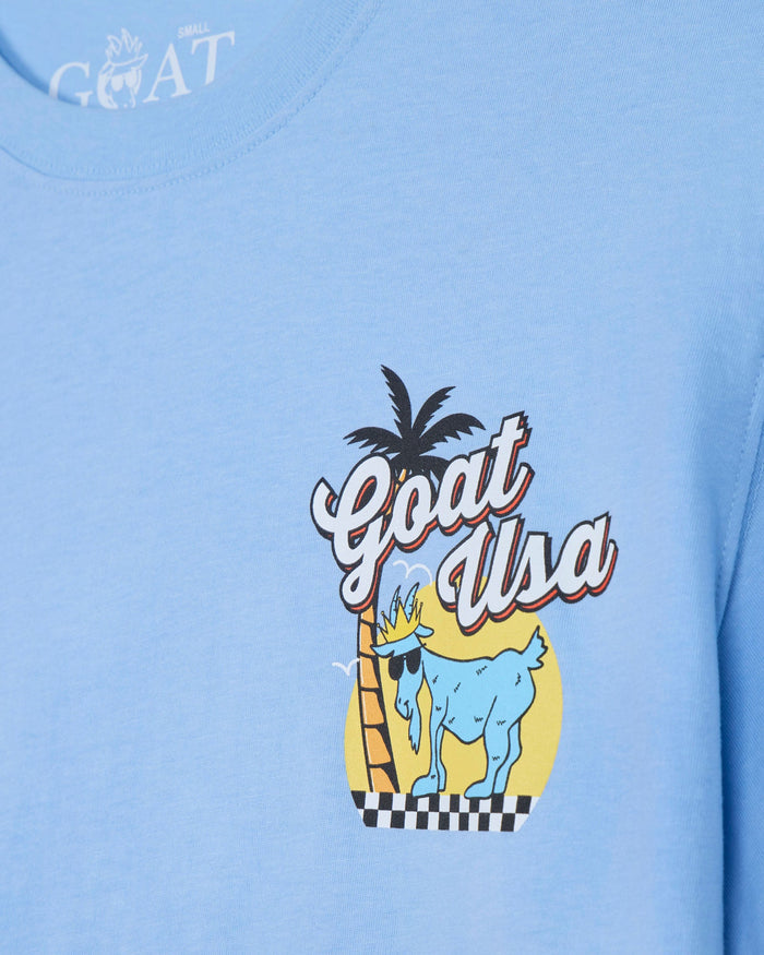 Light blue t-shirt with 'Goat USA' graphic design featuring a goat, palm tree, and text.