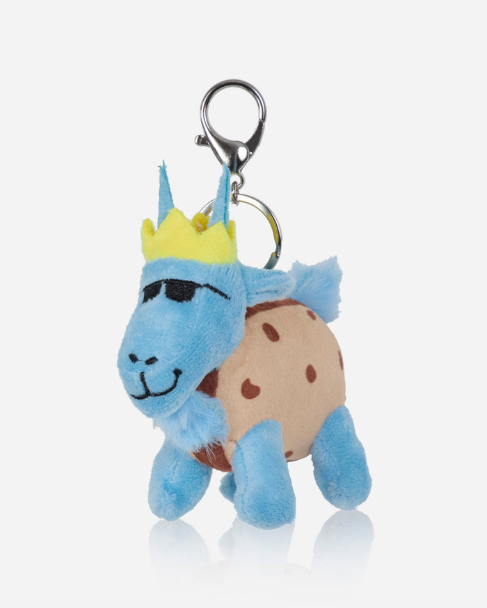 A plush bag charm shaped like a blue goat wearing a yellow crown and a tan shell with brown spots, attached to a silver metal clasp on a light gray background.