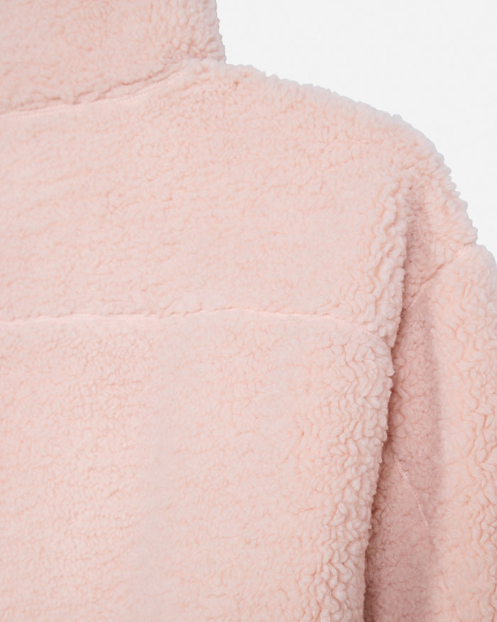 Close-up of a light pink sherpa fleece garment, showing the soft textured fabric and collar detail against a plain white background.