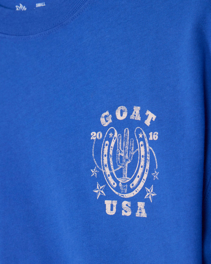 Close-up of a royal blue sweatshirt featuring a distressed white graphic on the chest with the text 'GOAT USA' and a cactus motif.