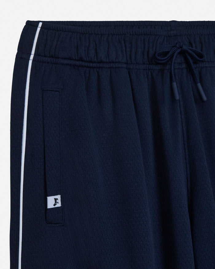 Close-up of dark navy athletic shorts with a white side stripe, elastic waistband, drawstring, and a small white logo patch.#color_navy-blazer