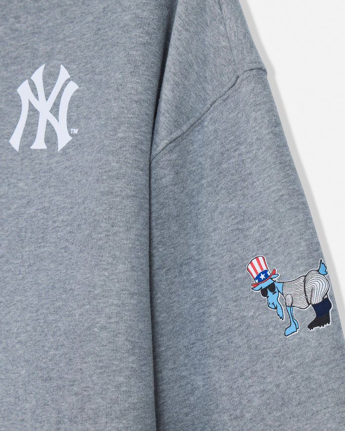 Close-up of a heather gray sweatshirt showing a white New York Yankees logo on the upper chest and a small multicolor graphic on the sleeve with a red, white, blue, and black design.